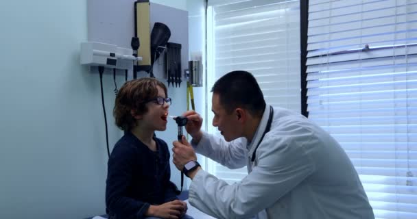 Side View Young Asian Male Doctor Examining Caucasian Boy Patient — Stock Video