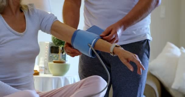 中年の白人男性白人女性家庭での血圧測定の正面 彼らは の相互対話します — ストック動画