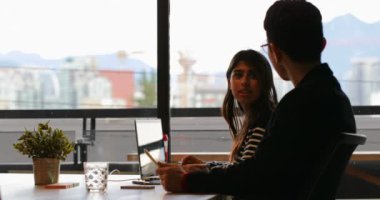 Genç Asya iş arkadaşları birbirleriyle etkileşim içinde modern ofis yan görünüm. 4 k masada oturan genç Asya iş arkadaşları