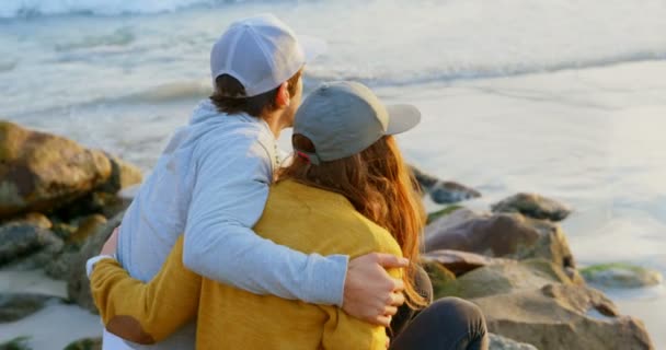 Vista Traseira Jovem Casal Caucasiano Sentado Rocha Olhando Para Mar — Vídeo de Stock