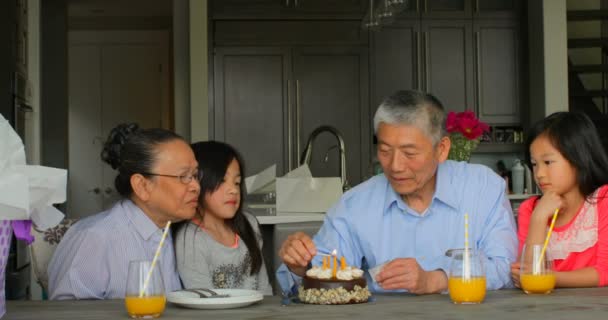 在一个舒适的家 多代亚洲家庭庆祝孙女生日4K 的老亚洲祖父闪电生日蛋糕蜡烛的正面景色 — 图库视频影像