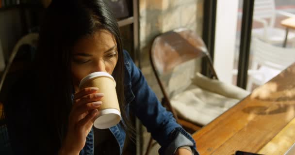 若いアジア女性コーヒーを飲むと カフェでノート パソコンを使用しての高角度のビュー のカフェで座っている若いアジア女性 — ストック動画