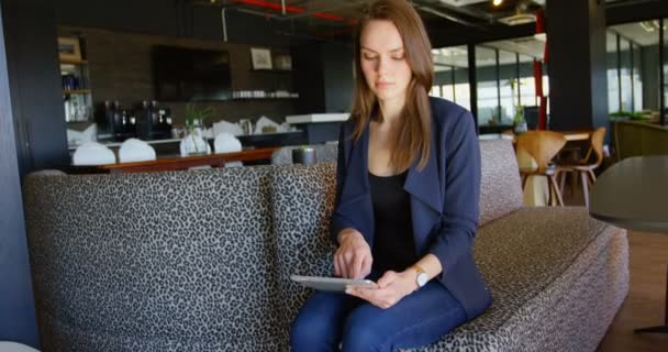 近代的なオフィスにデジタル タブレットに取り組んでいる若い白人実業家のフロント ビュー のソファに座って実業家 — ストック動画