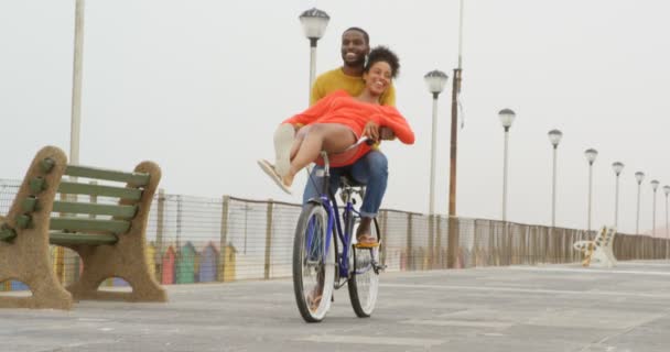 晴れた日にあるビーチの遊歩道カップル黒乗馬の自転車のフロント ビュー カップルの笑顔と楽しい — ストック動画