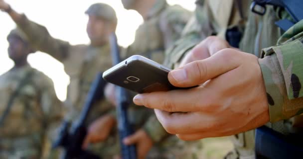 白人の軍事兵士が軍事訓練中に携帯電話を使用して中間のセクション チェックと の携帯電話でテキスト メッセージ — ストック動画