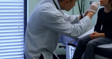 Genç Asyalı erkek yan görünüm aracında bir klinik muayene beyaz çocuk hastayla doktor. Erkek doktor hasta 4 k ile etkileşim