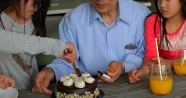 Onun Doğum günü pasta rahat bir ev bıçak ile kesme Sevimli Asya torunu önden görünümü. Çoklu nesil Asya Aile granddaughters Doğum günü 4 k kutluyor