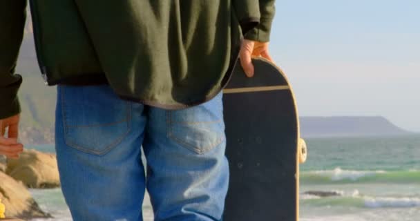 Vista Trasera Del Joven Pie Playa Mirando Mar Hombre Sosteniendo — Vídeo de stock