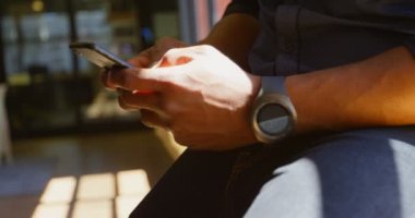 Genç işadamı manifatura modern bir ofis cep telefonunda Close-up. Pencere pervazına 4 k üzerinde oturan işadamı