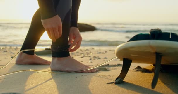 低部分的成人中高加索男性冲浪者绑冲浪板皮带在海滩上 冲浪者准备冲浪4K — 图库视频影像