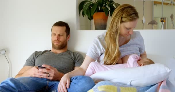 Vista Frontal Pai Usando Telefone Celular Enquanto Mãe Amamenta Para — Vídeo de Stock