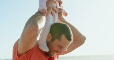 Orta yetişkin beyaz yan görünüm güneşli bir günde omuz taşıma Bebek Baba. 4 k bebekle oynarken baba