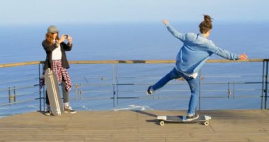 Dikiz genç erkek kaykaycı gözlem noktada kaykay sürme. Beyaz Genç Bayan kaykaycı fotoğrafları cep telefonu 4 k ile tıklayarak