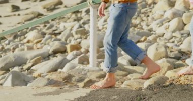 Beyaz aile güneşli bir günde kumsalda yürürken yan görünüm. Bir askı 4 k içinde taşıma bebek anne