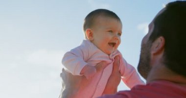 Orta yetişkin beyaz baba holding bebek Plajı'nda havadaki görünümünü güneşli bir günde arka. 4 k bebekle oynarken baba