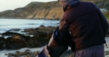 Yetişkin beyaz adam giyim sahilde kaldırma yan görünüm. Sörf için hazırlanıyor adam 4k