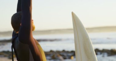 Yan görünüm Plajı'nda sörf önce ısınma ve germe yetişkin beyaz erkek sörfçü. Sörf için hazırlanıyor sörfçü 4k