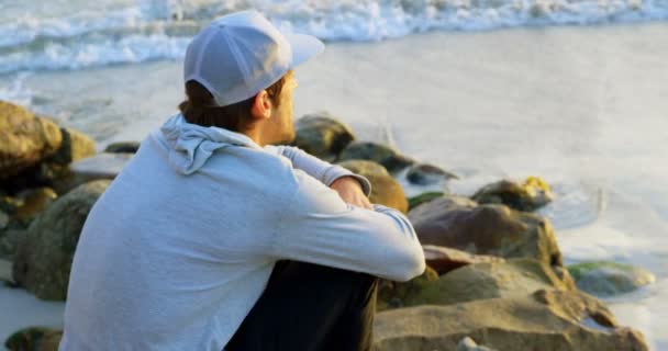 Side View Young Caucasian Man Sitting Rock Looking Sea Beach — Stock Video