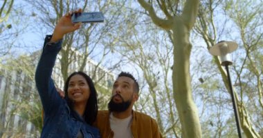 Genç Asyalı Çift selfie şehir içinde hareket eden telefon ile'ı tıklatarak düşük açılı görünümü. Birlikte 4 k şehirde oturan genç Asyalı Çift