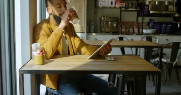 コーヒーを飲みながらカフェでデジタル タブレットを使用して若いのアジア男のフロント ビュー のカフェで座っている若いアジア男 — ストック動画