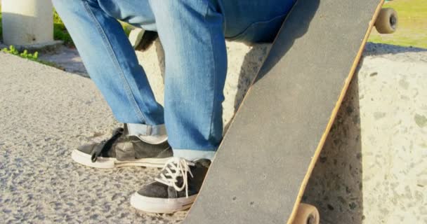 在人行道上使用手机的男子的侧视图 在阳光4K 的海滩附近拿着滑板的男子 — 图库视频影像