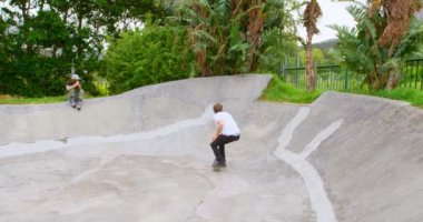 Önden Görünümü Genç beyaz adam pratik kaykay Kaykay Parkı içinde rampa üzerinde. Gün ışığında kaykay adam. Kaykay rampası 4 k üzerinde oturan arkadaş