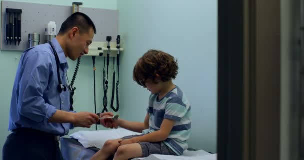 Side View Young Asian Male Doctor Examining Caucasian Boy Patient — Stock Video