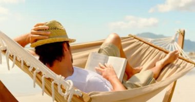 Beyaz delikanlı hamak Beach 4 k bir kitap okuma yan görünüm