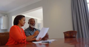 Olgun siyah çift rahat bir ev içinde aile içi faturaları tartışmaya açık bakış. Onlar 4 k yemek masada oturuyorlar