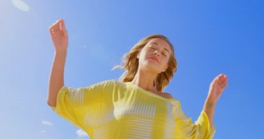 Sahilde duran genç Kafkas kadın düşük açılı görünümü. O gözleri kapalı duruyor ve saç 4 k eller