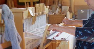 Eski beyaz kadın bir atölyede el dokuma makinesinde bez dokuma kıdemli yan görünüm. Pamuk iplik 4 k kullanıyor