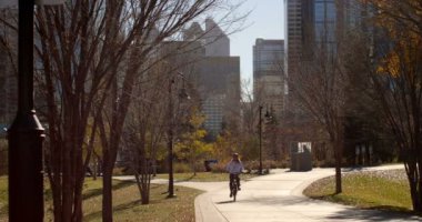 Genç Beyaz adam binicilik bisiklet park önden görünümü. Kaygısız adam şehirde sonbahar ağaç boyunca güneşli günde 4 k Bisiklete binme