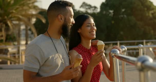 愉快的混血夫妇站在一个冰淇淋锥在长廊 在海上4K 看的混血情侣 — 图库视频影像