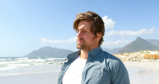 で髪のビーチに立っている若い白人男の側面図 — ストック動画