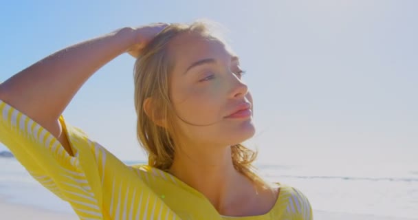 在海滩上放松的年轻白人妇女的前面 她双手站在头发上 把目光移开 — 图库视频影像