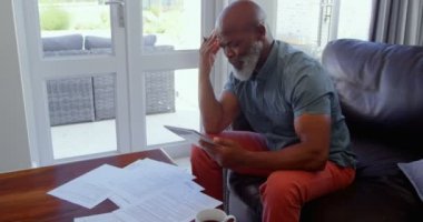 Olgun adam evde oturma odasında belgelerin imzalanması yan görünüm. O düşünme ve belgeleri 4 k arıyorsunuz