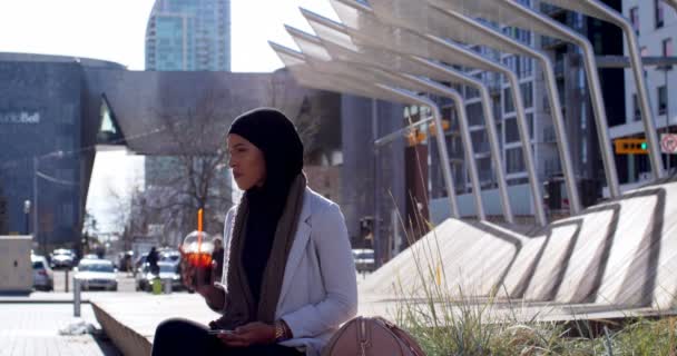 亚洲年轻女子在城市中使用手机戴头巾的侧视图 拿着冷饮4K 的年轻亚洲妇女 — 图库视频影像