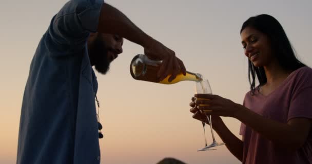 在日落时在海滩上喝香槟的混血儿 混血男子倒在玻璃4K — 图库视频影像