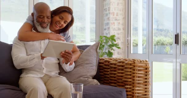 在一个舒适的家中使用数字平板电脑的快乐成熟的黑人夫妇的正面看法 从4K 后面拥抱男人的女人 — 图库视频影像
