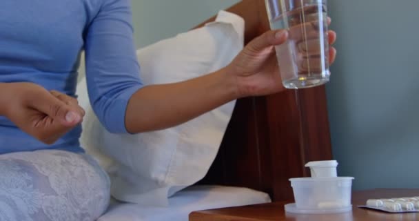 在舒适的家中 成熟女性用一杯水吃药的正面景观 生病的妇女坐在床4K — 图库视频影像