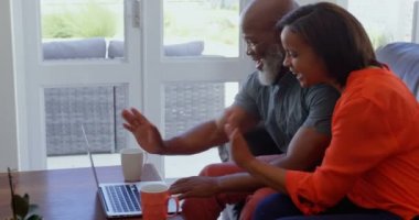 Olgun çift evde dizüstü bilgisayarda görüntülü arama yapma yan görünüm. Gülümseyen ve 4 k el hareketi