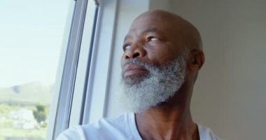 Olgun zenci adam rahat bir ev penceresinde aramak yan görünüm. Dalgın ve üzgün 4 k o