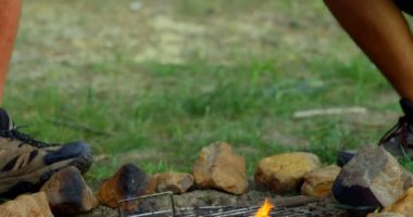 Hot dog'kadınlarda cep telefonuyla çadırda kamp ateşi kavurma erkekler. Birlikte 4 k ormanda kamp arkadaşları
