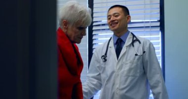 Genç Asyalı erkek doktor klinikte üst düzey hasta ile etkileşim. Küçük Asya erkek doktor danışmanlık üst düzey hasta 4k