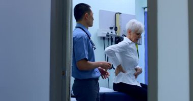 Klinik kıdemli bir hastada inceleyerek genç Asyalı erkek doktor. Genç Asyalı erkek doktor üst düzey hasta 4 k ile etkileşim