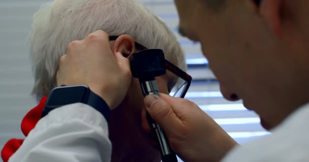 Junger Asiatischer Arzt Untersucht Einen Älteren Patienten Mit Otoskop Der — Stockvideo