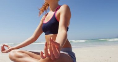 Kadın güneşli bir günde Yoga Plajı'nda gerçekleştiriliyor. Sakin deniz ve güzel gökyüzü içinde belgili tanımlık geçmiş 4k
