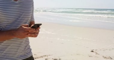 Güneşli bir günde beach adlı cep telefonu kullanan adam. Bir cep telefonu 4 k tutan adam