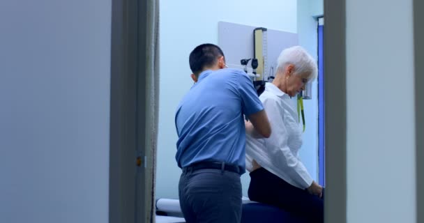 Unga Asiatiska Manliga Läkare Att Undersöka Senior Patient Kliniken Ung — Stockvideo