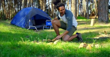 Güneşli bir günde ormandaki şenlik ateşi hazırlayan adam. Adam holding taş 4k